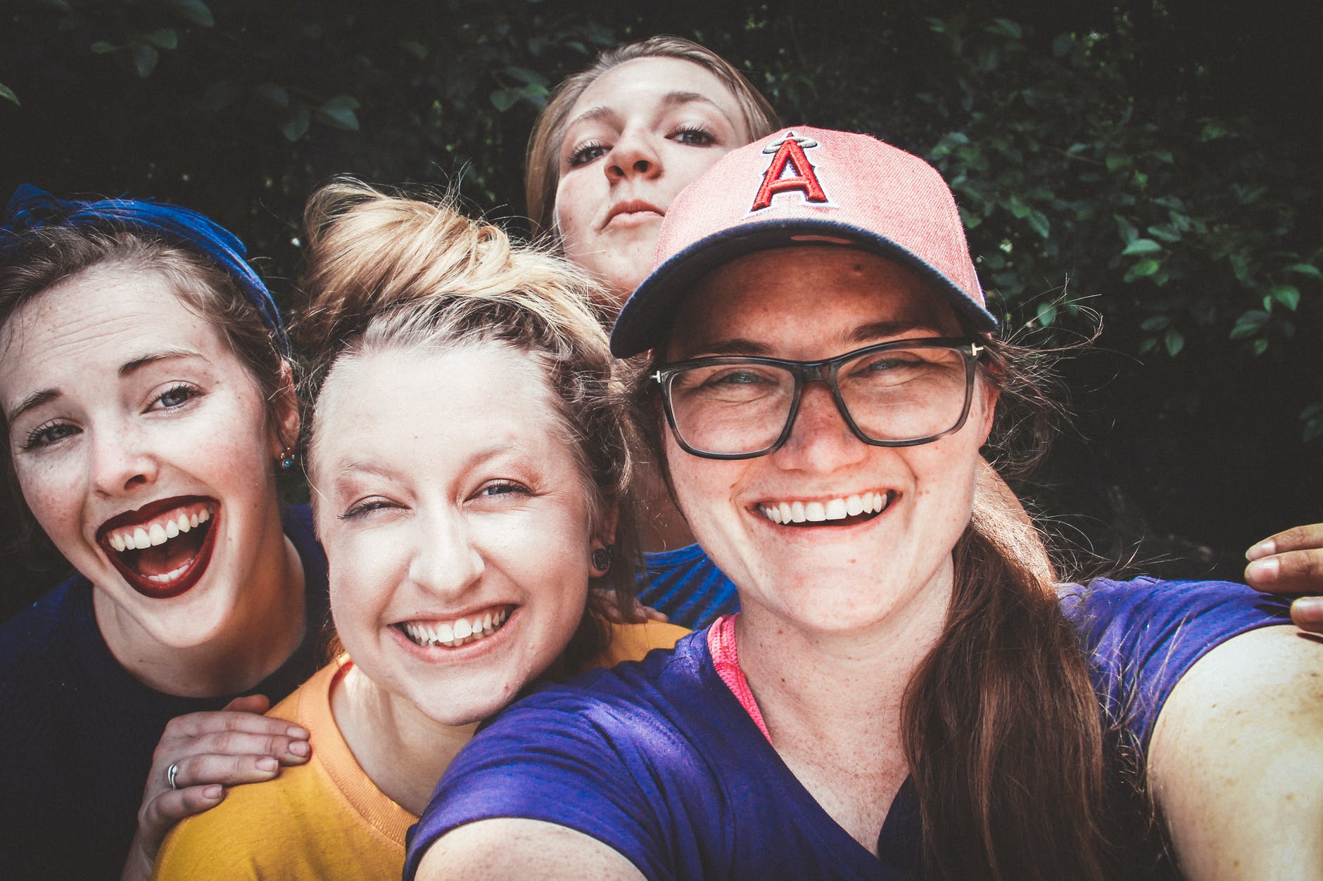 four women in front of green bushes